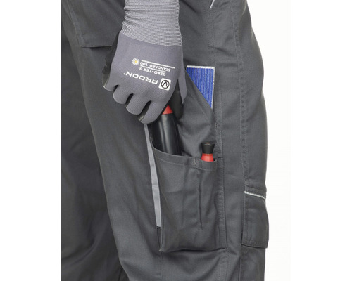 Prim-plan cu pantaloni de lucru cu scule în buzunar, purtați cu mănuși de lucru