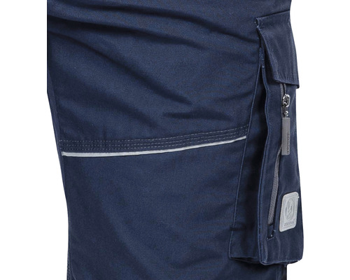 Detaliu al unor pantaloni de lucru albaștri cu buzunar și bandă reflectorizantă