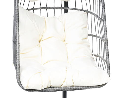 Prim-plan cu un scaun din ratan cu pernă de șezut de culoarea cremei.