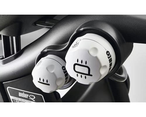 Prim-plan cu două butoane rotative albe pentru controlul unui grătar cu gaz.