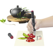 Scenă cu o mână care desenează o cireașă pe hârtie cu un marker, cu un ceainic în fundal