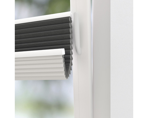 Prim-plan cu un jaluzea plisată gri și albă pe fereastră