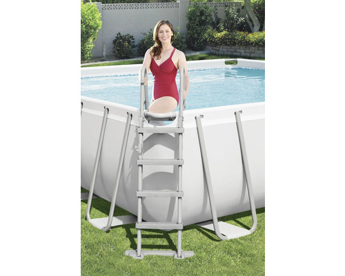 Femeie urcând pe o scară într-o piscină dreptunghiulară din grădină