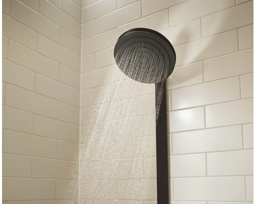 Cap de duș cu jet de apă în fața unui perete cu faianță