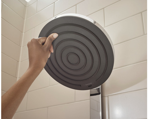 Persoană care ține o pară de duș în baie.