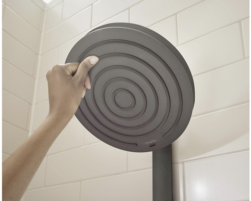 O mână atinge o pară de duș rotundă în baie