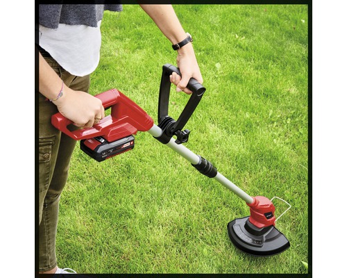 O persoană utilizează un trimmer de gazon în grădină.