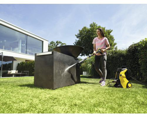 Femeie curăță sculptura exterioară cu un curățător cu presiune în grădină.