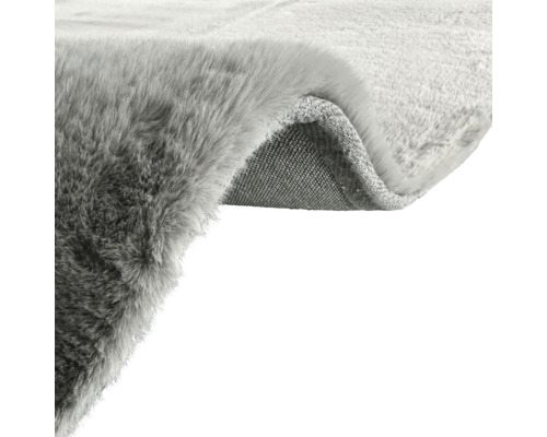 Vizualizare detaliată a unui covor gri cu suprafață pufoasă și spate textil