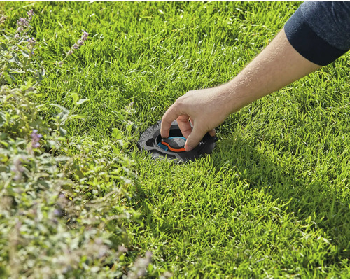O persoană ajustează un aspersor de gazon încastrat în gazon.