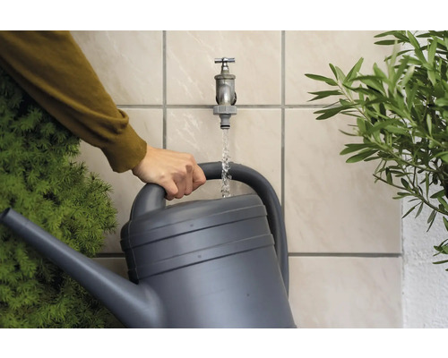 O stropitoare este umplută cu apă sub un robinet pentru a uda plantele.