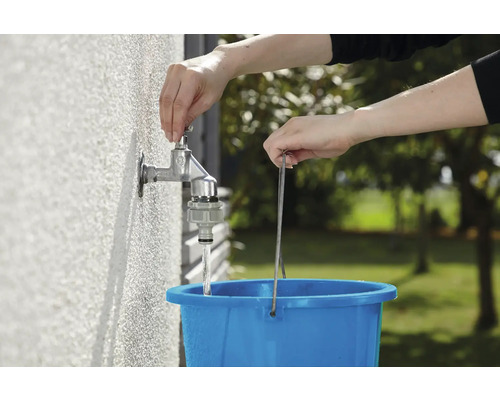 O persoană umple o găleată albastră cu apă dintr-un robinet exterior.