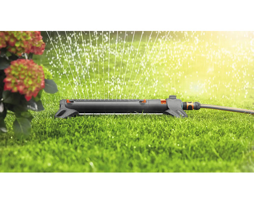 Aspersor de gazon în funcțiune pe o suprafață verde