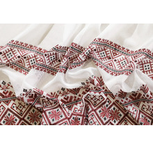 Prim-plan cu țesătură albă cu broderie roșie