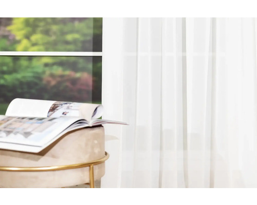 Scenă cu perdea glisantă albă, taburet și revistă într-o cameră luminoasă