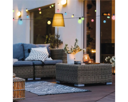 Terasa cu set de mobilier din ratan, covor și lanț de lumini
