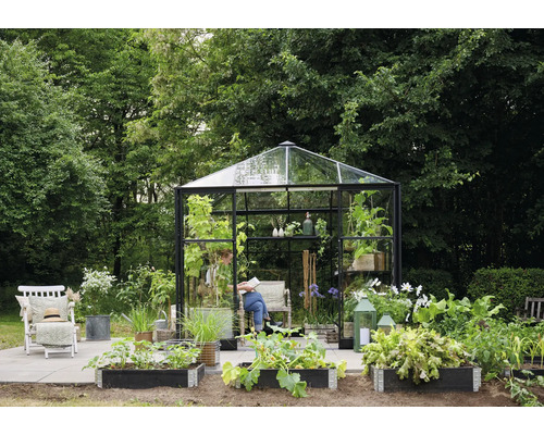 Scenă de grădină cu seră, straturi înălțate, scaun și persoană