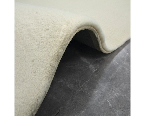 Vizualizare detaliată a unui covor deschis la culoare, cu fibre textile, pe o podea