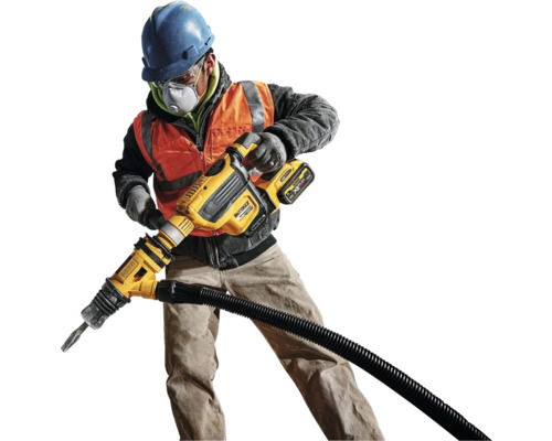 Un muncitor în construcții cu cască de protecție, ochelari de protecție și mască de protecție respiratorie operează un ciocan demolator cu racord pentru aspirator.