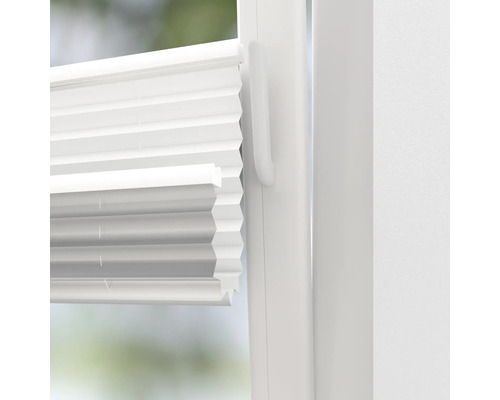 Prim-plan cu un jaluzele plisate albe pe o fereastră