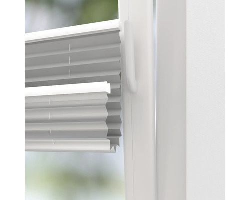 Prim-plan al unui jaluzele plisate albe pe o fereastră