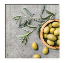 Natură statică cu măsline într-un bol de lemn și ramură de măslin pe fundal de beton