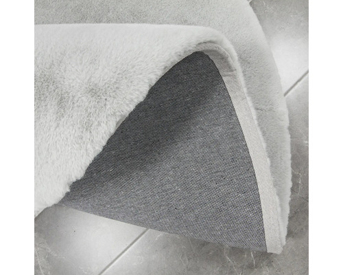 Vizualizare detaliată a unui covor de culoare deschisă cu fibre și spate din material textil