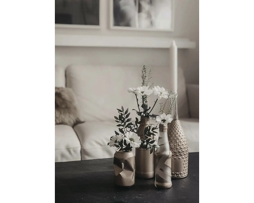 Scenă decorativă de masă cu flori în vaze în fața unei canapele