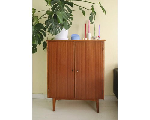 Dulap din lemn cu două uși și patru picioare, decorat cu o plantă de interior și lumânări