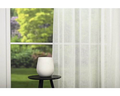 Cortină decorativă albă în fața unei ferestre cu o grădină în fundal