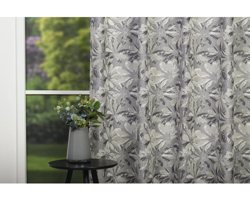Cortină decorativă cu model floral lângă o masă cu o vază de flori.