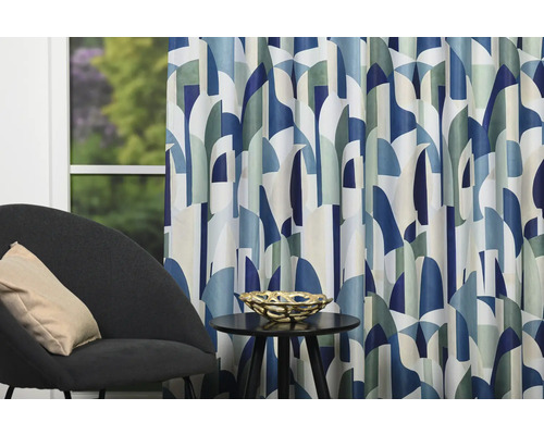 Cortină decorativă cu model geometric lângă un fotoliu și o măsuță laterală.