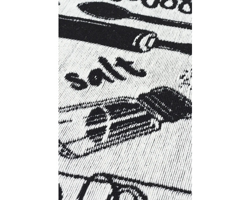 Prim-plan cu un prosop de bucătărie cu articole de bucătărie imprimate, cum ar fi o lingură de amestecat și o solnita.