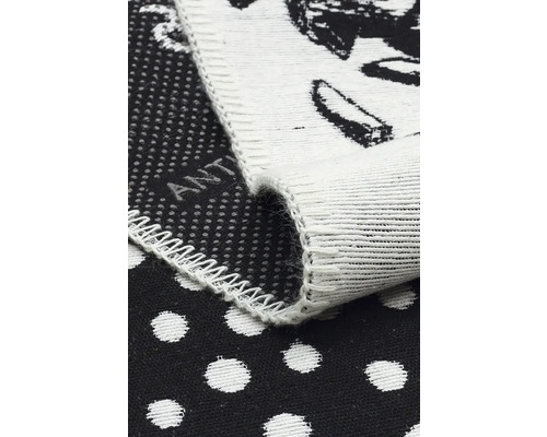 Prim-plan cu un covoraș de baie negru cu buline albe și bordură albă