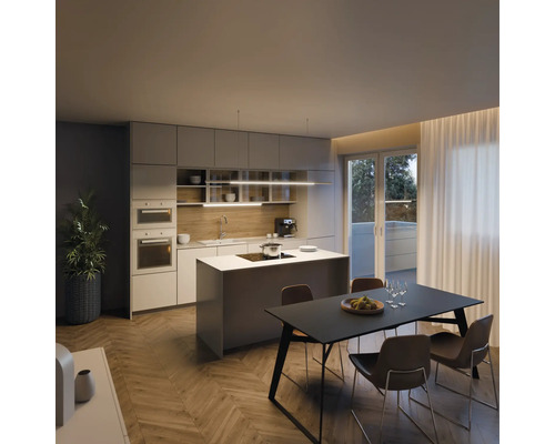 Bucătărie modernă cu insulă de gătit, masă de sufragerie și scaune într-o cameră luminoasă.