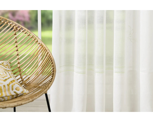 Fereastră decorativă cu perdele și mobilier din ratan.