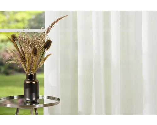 Flori uscate decorative în vază pe o măsuță laterală în fața ferestrei cu perdea