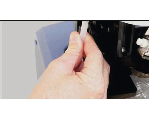 O persoană introduce un furtun într-un dispozitiv.