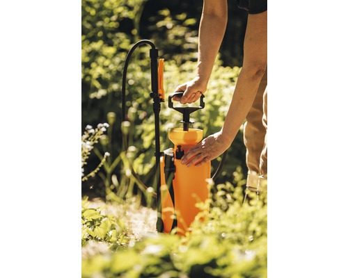 O persoană manevrează un pulverizator de grădină în aer liber.