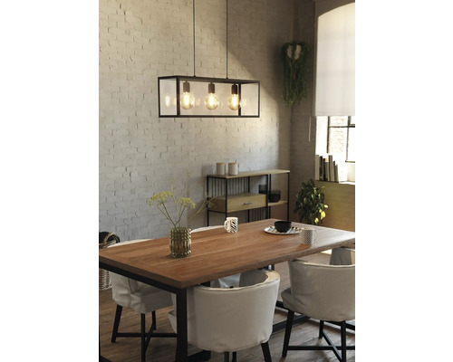 Sufragerie cu masă, scaune, raft și o lampă suspendată cu trei becuri.