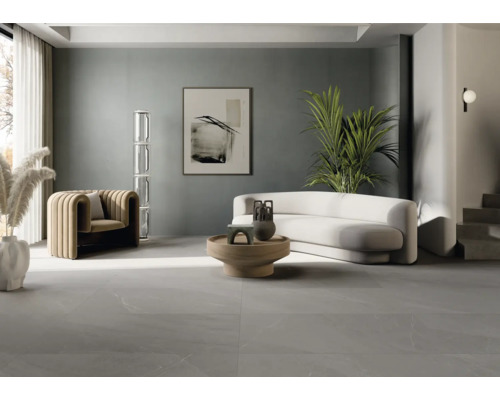 Living luminos cu fotoliu, canapea, masă și pardoseală cu gresie.