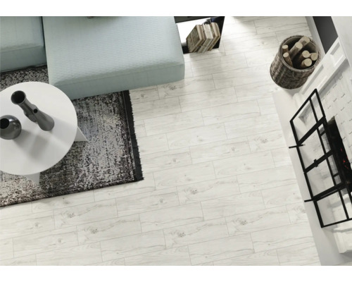 Cameră de zi luminoasă cu gresie cu aspect de lemn, canapea, masă, șemineu și decorațiuni pentru o atmosferă luminoasă și prietenoasă.