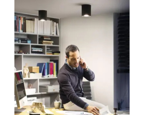 Bărbat așezat pe un birou într-un birou cu spoturi de tavan