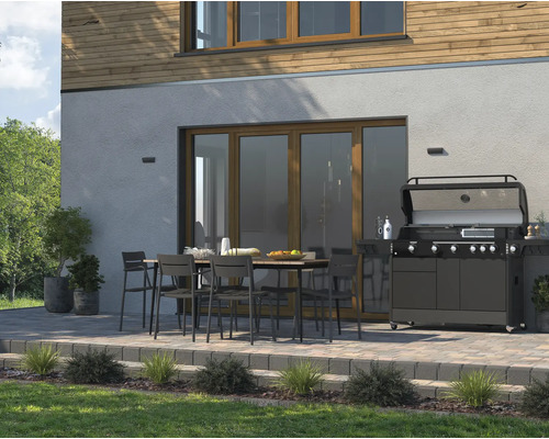 Terasa cu masă de dining, scaune și grătar pe gaz în fața unei case.