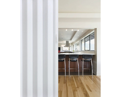 Vedere printr-o ușă pliabilă spre o bucătărie cu bar și scaune de bar