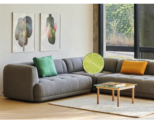 Canapea de colț gri cu perne, măsuță de cafea și opere de artă înrămate într-o sufragerie luminoasă