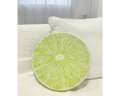 Pernă rotundă cu model de lămâie verde pe un pat