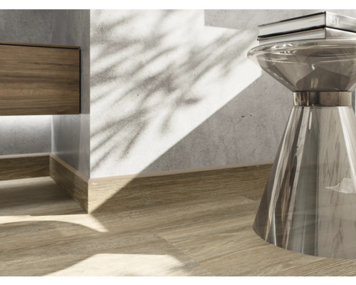 Prim-plan al unui interior cu podea din lemn, plintă și măsuță laterală