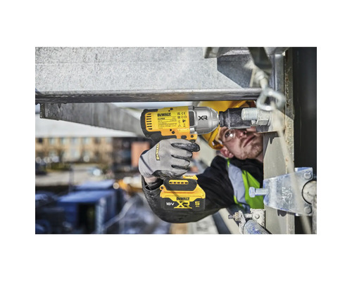 Un bărbat folosește o cheie de impact galbenă DeWalt, cu acumulator, pentru a fixa un șurub pe o structură metalică.