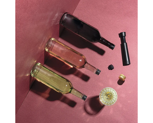 Trei sticle de vin umplute cu vin alb, vin roze și vin roșu sunt așezate pe podea, împreună cu dopuri și o pompă de vin.